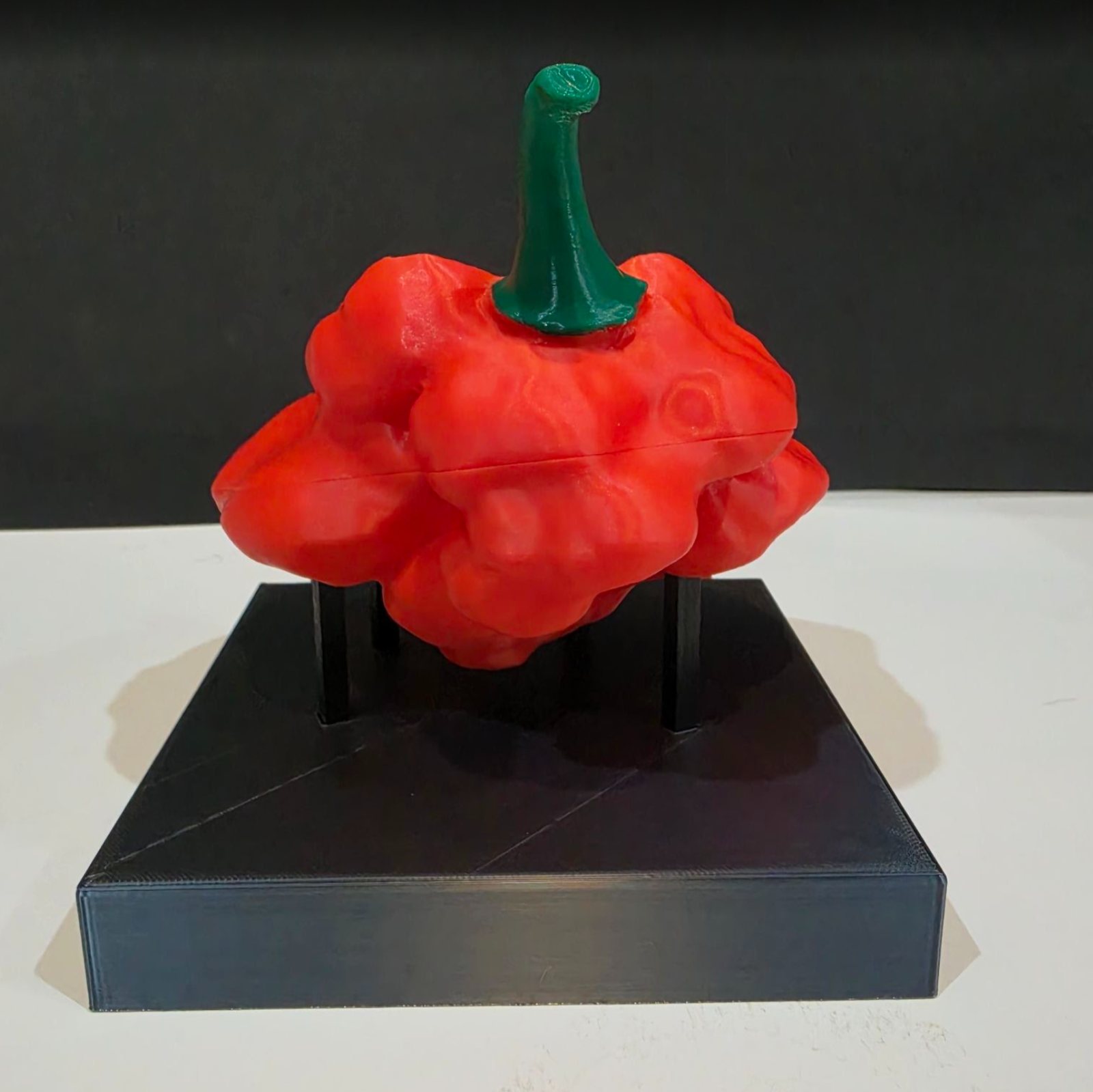 A sculpted pepper display piece on a black base
